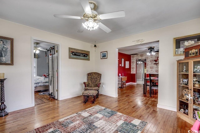 sitting room with light wood-style floors, baseboards, and ceiling fan