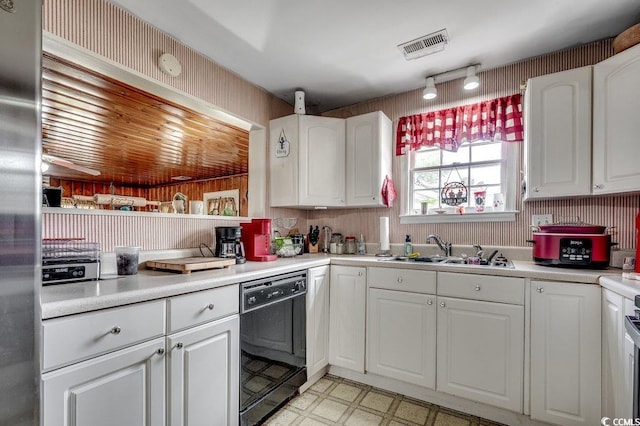 kitchen featuring light floors, white cabinets, visible vents, dishwasher, and a sink