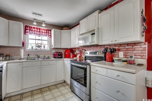 kitchen with white microwave, stainless steel electric range oven, visible vents, light floors, and a sink