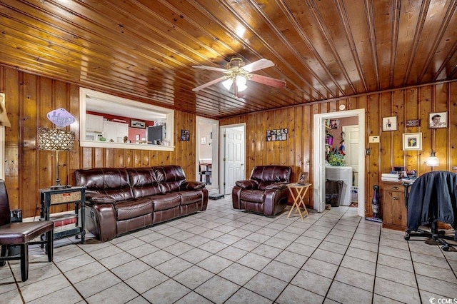 living room with wood walls, wooden ceiling, light tile patterned floors, and ceiling fan