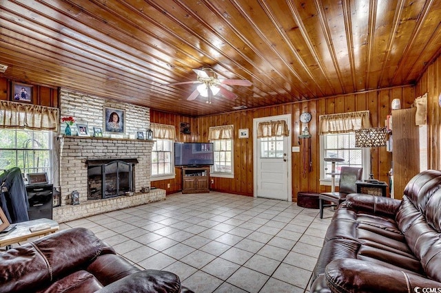 tiled living room with wood ceiling, wood walls, ceiling fan, and a fireplace