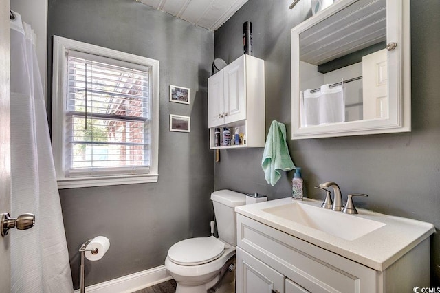 full bathroom with toilet, vanity, and baseboards