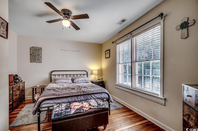 bedroom featuring visible vents, baseboards, hardwood / wood-style floors, and a ceiling fan