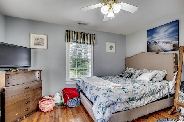 bedroom with wood finished floors, ceiling fan, and visible vents