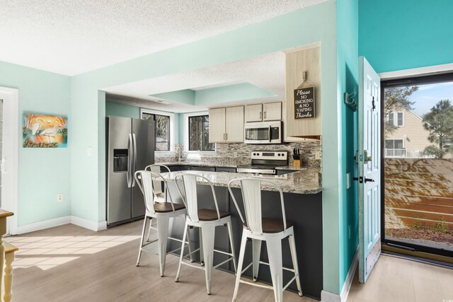 1521 Edge Dr, North Myrtle Beach, SC 29582 - kitchen with light stone countertops, a peninsula, light wood-type flooring, stainless steel appliances, and backsplash