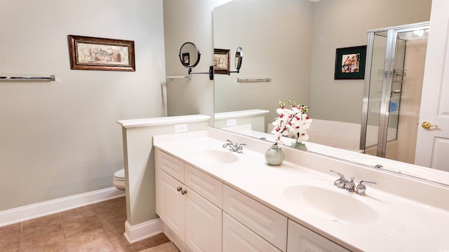 bathroom featuring a sink, baseboards, double vanity, and toilet
