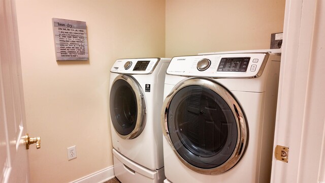laundry room with baseboards, separate washer and dryer, and laundry area