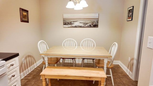 dining room featuring dark tile patterned flooring, a notable chandelier, and baseboards