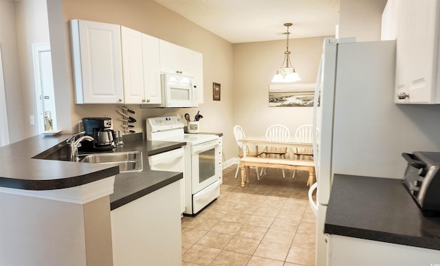 kitchen featuring white appliances, a peninsula, dark countertops, white cabinets, and a sink