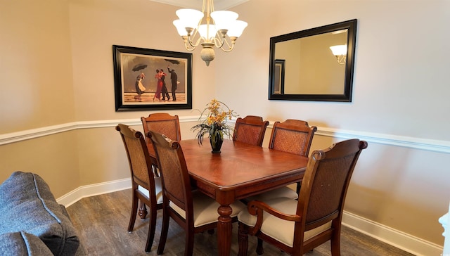 dining space featuring a chandelier, baseboards, and wood finished floors