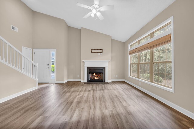 1545 Spinnaker Dr Unit 2C, North Myrtle Beach, SC 29582 - unfurnished living room featuring high vaulted ceiling, stairs, wood finished floors, a fireplace with flush hearth, and baseboards