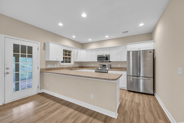 1545 Spinnaker Dr Unit 2C, North Myrtle Beach, SC 29582 - kitchen with stainless steel appliances, light wood finished floors, a peninsula, white cabinets, and baseboards