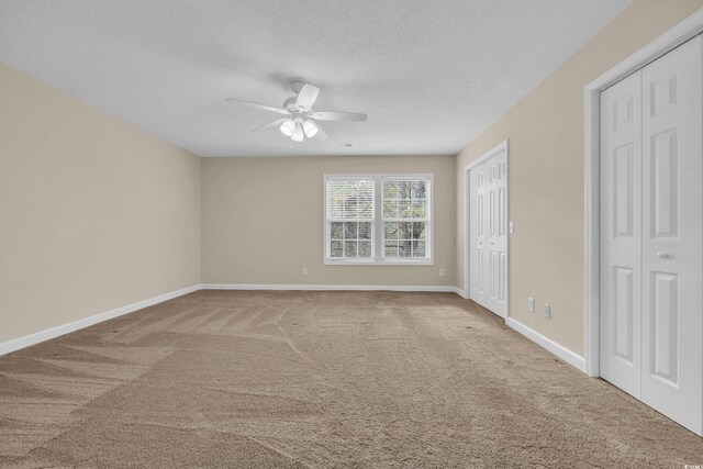 1545 Spinnaker Dr Unit 2C, North Myrtle Beach, SC 29582 - unfurnished bedroom with carpet, multiple closets, a textured ceiling, baseboards, and a ceiling fan