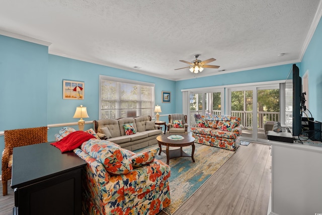 living area with a textured ceiling, hardwood / wood-style floors, crown molding, and ceiling fan
