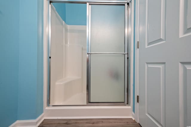 full bathroom with a shower stall and wood finished floors