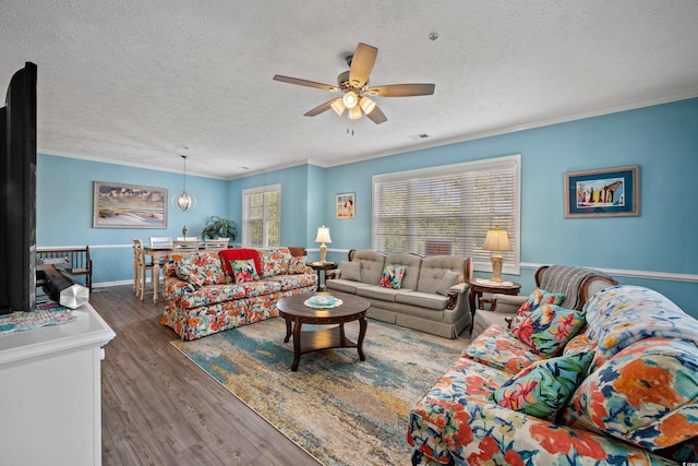 living room with a textured ceiling, crown molding, a ceiling fan, visible vents, and wood finished floors