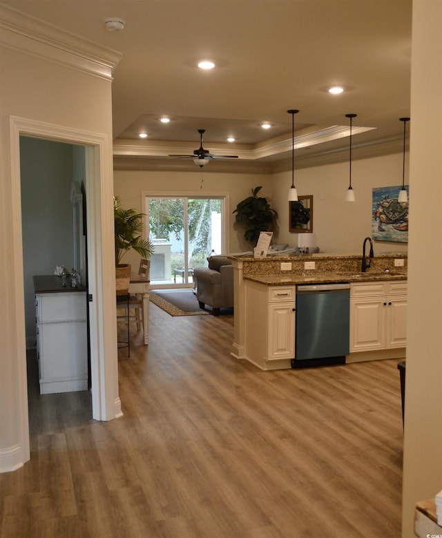 kitchen with stainless steel dishwasher, a tray ceiling, crown molding, open floor plan, and light wood-style flooring