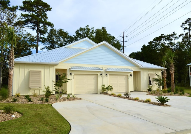 view of front of house featuring board and batten siding, an attached garage, driveway, and metal roof