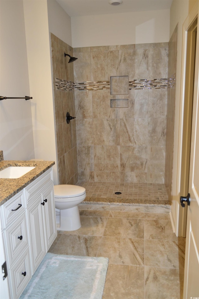 bathroom featuring tiled shower, toilet, and vanity