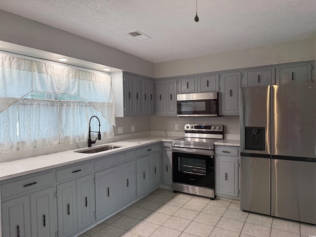 2108 Brunswick Cir, Little River, SC 29566 - kitchen with appliances with stainless steel finishes, gray cabinets, a textured ceiling, light tile patterned floors, and light stone counters