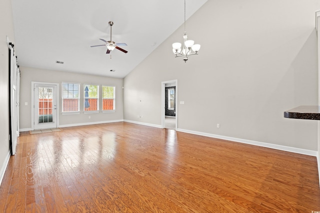 826 Sand Binder Dr, Myrtle Beach, SC 29579 - unfurnished living room with a ceiling fan, wood finished floors, high vaulted ceiling, a barn door, and a chandelier