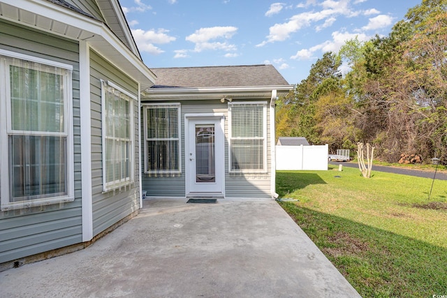 406 Pritchard St, Myrtle Beach, SC 29588 - view of exterior entry with a lawn, fence, a patio area, and roof with shingles
