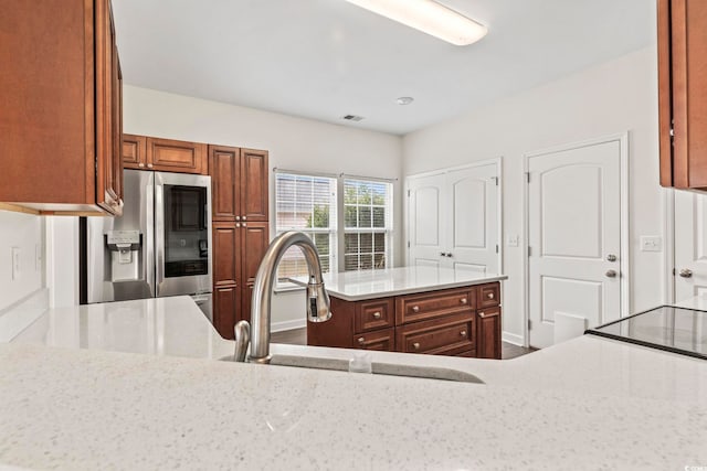 601 Seth Ln, Longs, SC 29568 - kitchen featuring stainless steel refrigerator with ice dispenser, a sink, light stone counters, brown cabinetry, and a center island