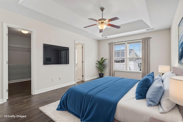 601 Seth Ln, Longs, SC 29568 - bedroom featuring a tray ceiling, a walk in closet, dark wood-type flooring, baseboards, and a closet