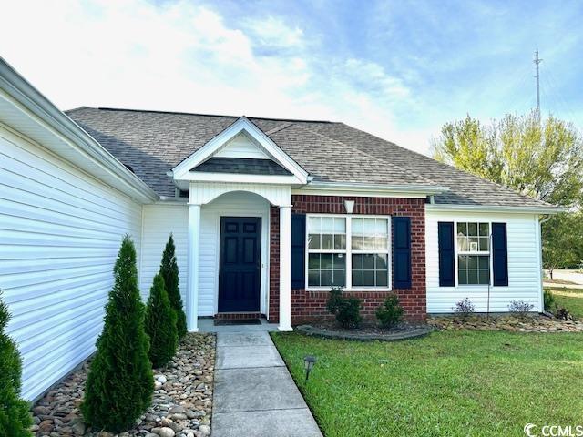 232 Marbella Dr, Murrells Inlet, SC 29576 - view of exterior entry with a yard, brick siding, and roof with shingles