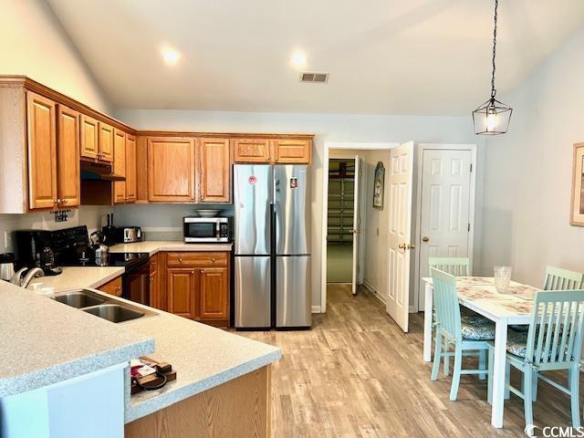 232 Marbella Dr, Murrells Inlet, SC 29576 - kitchen with stainless steel appliances, under cabinet range hood, vaulted ceiling, light countertops, and a sink