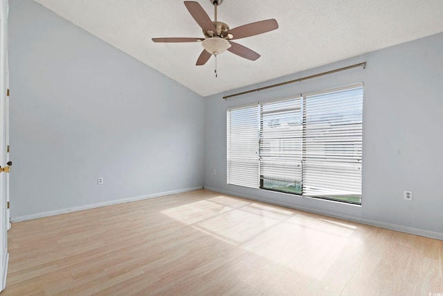 spare room with baseboards, a ceiling fan, light wood-style floors, and lofted ceiling