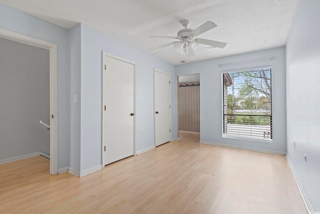 unfurnished bedroom featuring multiple closets, baseboards, and a textured ceiling