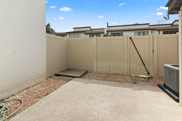 view of patio / terrace featuring a fenced backyard, central AC unit, and a gate