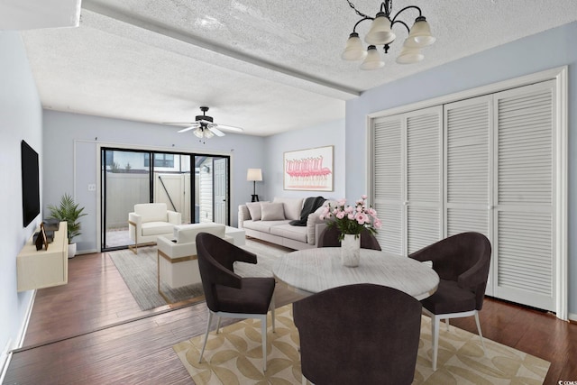 living room with ceiling fan with notable chandelier, baseboards, wood finished floors, and a textured ceiling