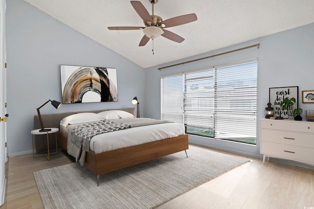 bedroom featuring light wood-style floors, baseboards, a ceiling fan, and lofted ceiling