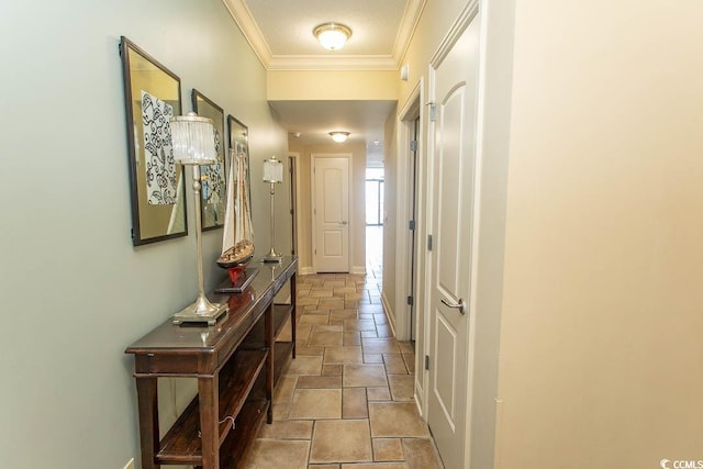 corridor featuring stone tile floors, crown molding, and baseboards