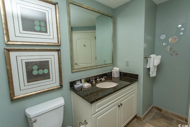 bathroom featuring baseboards, toilet, and vanity