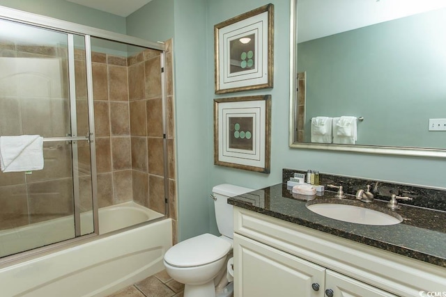 bathroom with vanity, combined bath / shower with glass door, tile patterned flooring, and toilet