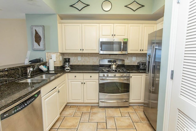 kitchen with appliances with stainless steel finishes, tasteful backsplash, a sink, a toaster, and dark stone countertops