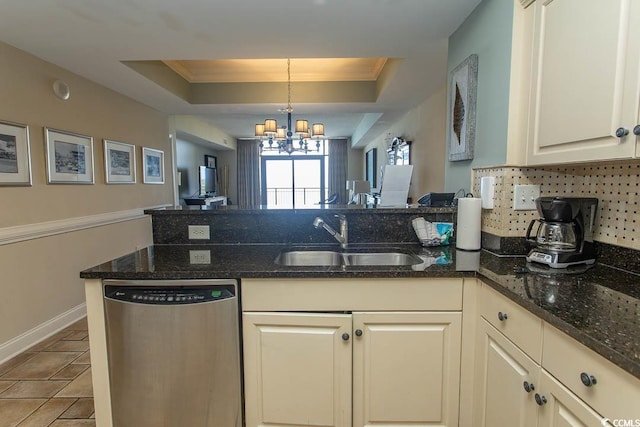 kitchen featuring a peninsula, dishwasher, a tray ceiling, a sink, and backsplash