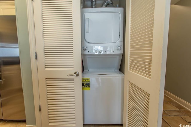 washroom with laundry area, stacked washer / drying machine, baseboards, and tile patterned flooring