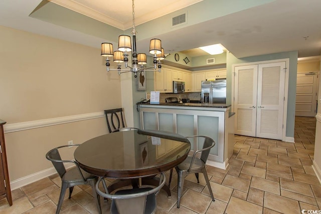 dining area with an inviting chandelier, ornamental molding, stone finish flooring, and visible vents