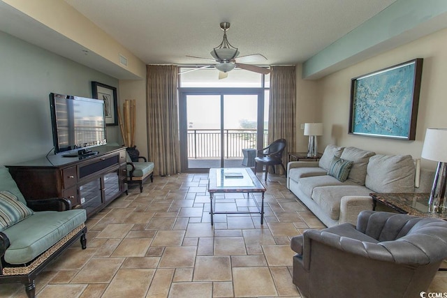 living area with stone finish flooring, a ceiling fan, visible vents, and floor to ceiling windows