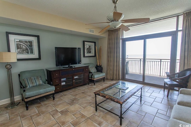 living area with visible vents, baseboards, a textured ceiling, a ceiling fan, and stone finish flooring