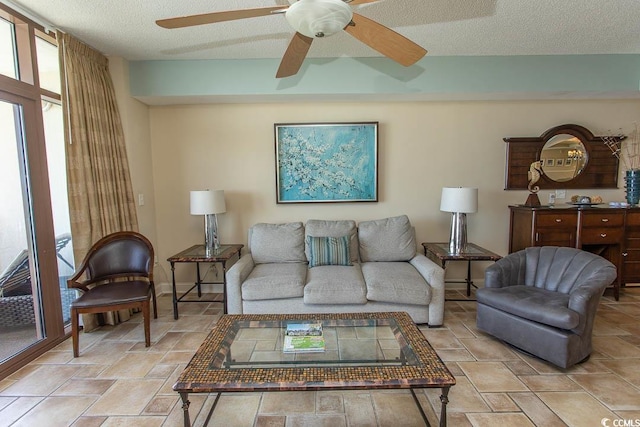 living area featuring ceiling fan, a textured ceiling, and stone tile floors