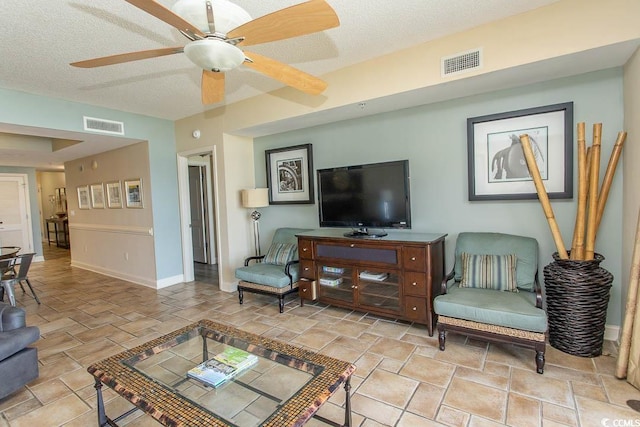 living room with visible vents, a textured ceiling, baseboards, and ceiling fan
