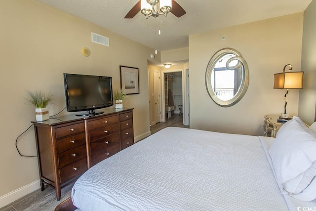 bedroom with baseboards, a ceiling fan, wood finished floors, and visible vents