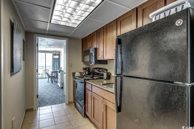 1105 S Ocean Blvd Unit 502, Myrtle Beach, SC 29577 - kitchen featuring black appliances, light tile patterned flooring, brown cabinets, baseboards, and dark stone counters