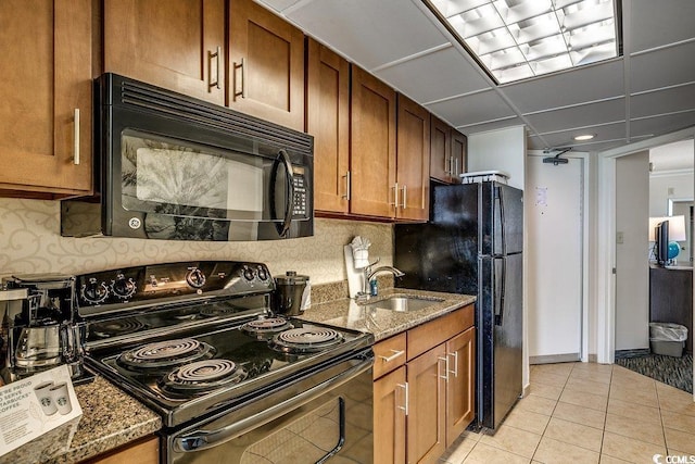 1105 S Ocean Blvd Unit 502, Myrtle Beach, SC 29577 - kitchen with black appliances, a sink, dark stone counters, light tile patterned flooring, and brown cabinetry