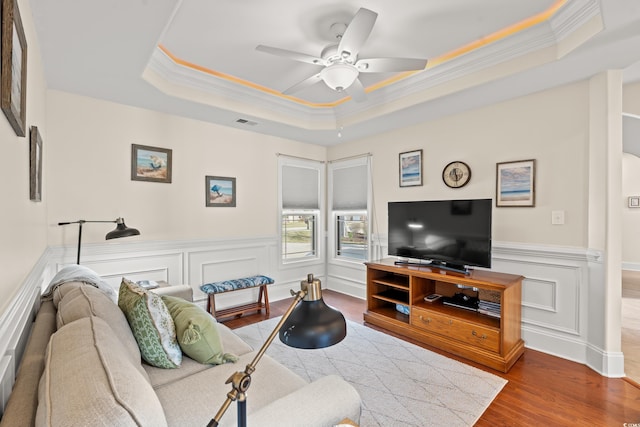 2039 Woodburn Dr, Myrtle Beach, SC 29579 - living area featuring ornamental molding, a tray ceiling, wood finished floors, ceiling fan, and wainscoting